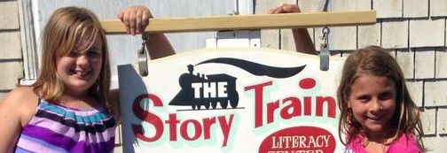 Two girls with The Story Train Literacy Program sign